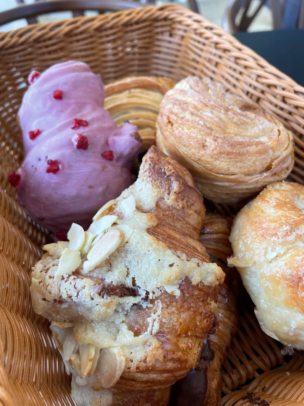 Canasta con bollería recién horneada: croissants de almendra y piezas de frutos rojos